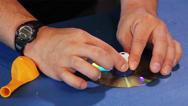 Press the sports bottle cap to the CD and hold it for a few moments while the glue sets up.